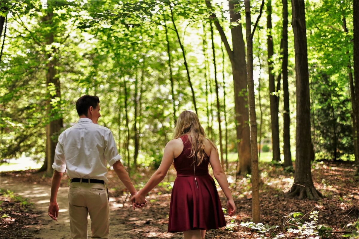 A couple goes for a walk in the forest in casual clothes. In this way, they ensure sufficient movement even during the training break and thus already provide a good foundation for the next sports season.