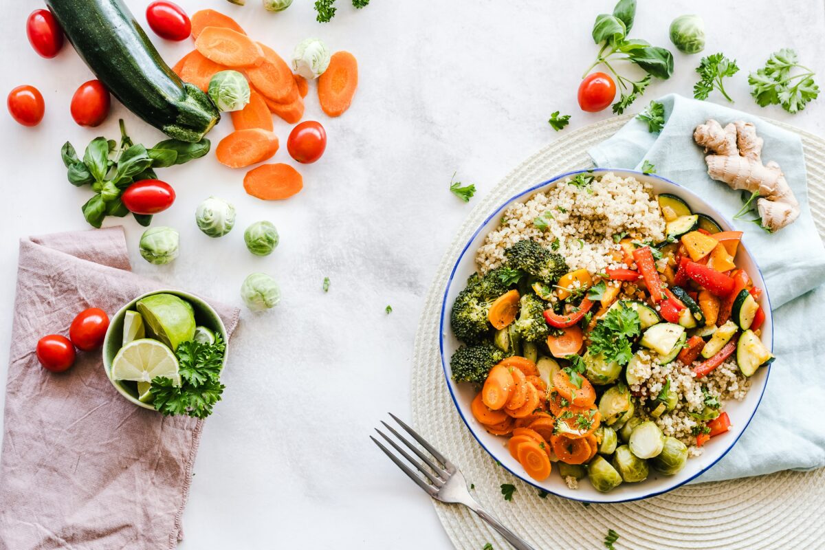 On the right side: plate with vegetables and couscous to watch Left side: vegetables loose such as sliced carrots, tomatoes and limes in the bowl.