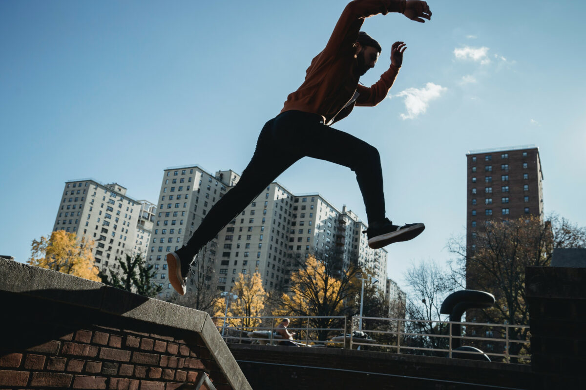 A man doing parcour in a typical city landscape.